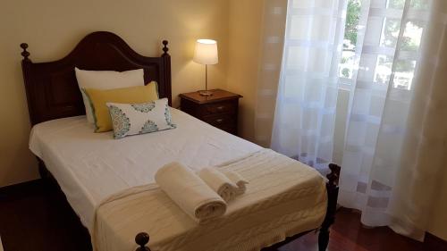 a bedroom with a bed with white sheets and a window at Villa Mucifal D in Sintra