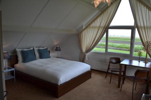 a hotel room with a bed, chair, table and window at Bed & Breakfast Giethoorn in Giethoorn