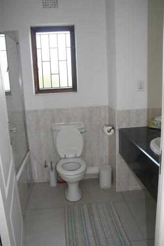 a bathroom with a toilet and a sink and a window at Keurbooms River Lodge 21 in Keurboomstrand