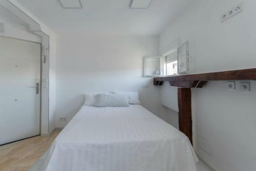 Dormitorio blanco con cama y mesa de madera en Mendez Alvaro ATOCHA en Madrid