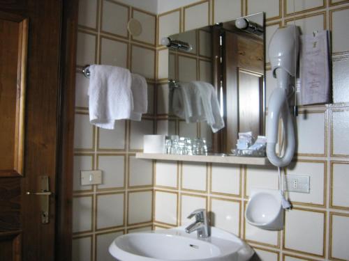 a bathroom with a sink and a mirror and towels at Hotel Albergo Dolomiti in San Vito di Cadore