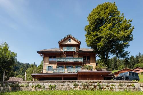 a large wooden house with a tree at La FERME des Lombardes in Saint-Jean-de-Sixt