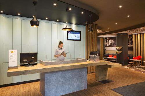 a woman standing at a counter in a lobby at Ibis Budapest Heroes Square in Budapest