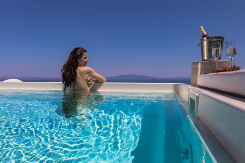 Una donna seduta in piscina su una barca di Elysian Santorini a Oia
