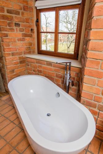 a white bath tub in a bathroom with a brick wall at Zamek Topacz in Wrocław