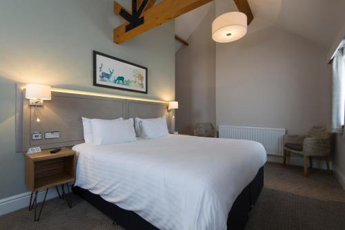 una habitación de hotel con una cama grande con sábanas blancas en Green Dragon, Welton by Marston's Inns en South Cave