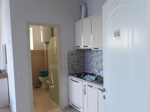 a small kitchen with white cabinets and a refrigerator at Residence Kullat in Velipojë