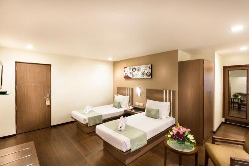 una camera d'albergo con due letti e un divano di The Lotus Apartment Hotel, Venkatraman Street a Chennai