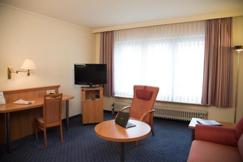 a hotel room with a couch and a table and a tv at Parkhotel Bad Homburg in Bad Homburg vor der Höhe