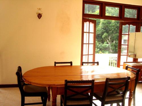 una sala da pranzo con tavolo e sedie in legno di Layathraa Kandy a Kandy