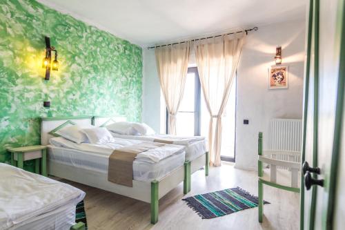 a bedroom with two beds with green wallpaper at Vinalia - Conacul din Ceptura in Ceptura de Jos