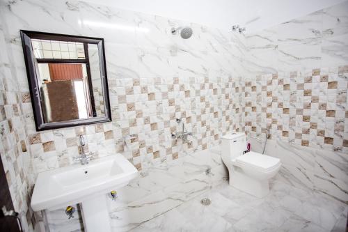 La salle de bains est pourvue de toilettes, d'un lavabo et d'un miroir. dans l'établissement Hotel Shiv Kripa, à Dehradun