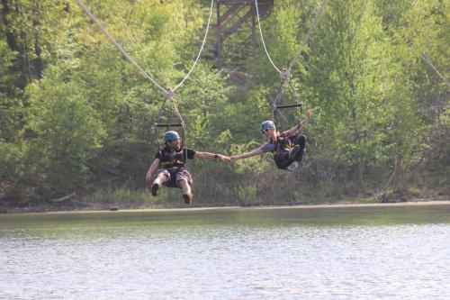 two people jumping into the water on a rope swing over a lake at The Appalachian at Mountain Creek in Vernon