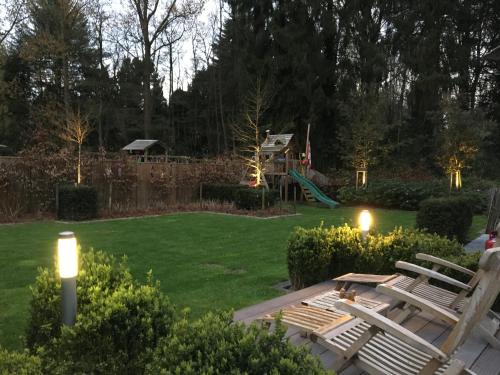 a backyard with two chairs and a playground with a slide at Stropershuisje in Stekene