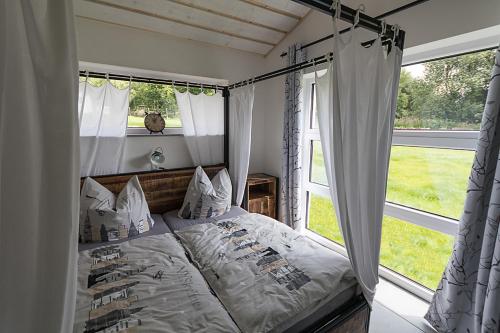a bedroom with a bed with a canopy and windows at Selke´s exklusives Ferienhaus in Clausthal-Zellerfeld