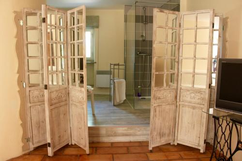 een badkamer met 2 houten deuren en een spiegel bij Mas de la Gonnette in Venasque