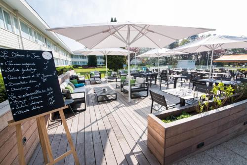 a restaurant with tables and umbrellas and a chalkboard at Novotel Lille Aéroport in Lesquin