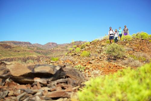 a group of people walking on a rocky mountain at Casa León Royal Retreat in Maspalomas