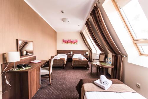 チェホチネクにあるHotel Austeria Conference & Spaのベッド3台と鏡が備わるホテルルーム
