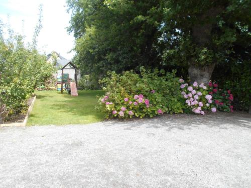 un jardín con flores rosas y un árbol en Fée Morgane - Chambres, en Saint-Coulomb
