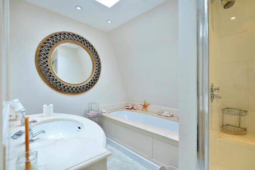 a bathroom with a tub and a mirror on the wall at Ennismore Mews in London