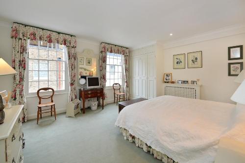 a bedroom with a bed and a desk and two windows at Ennismore Mews in London