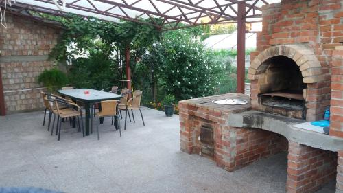 un patio de ladrillo con mesa y horno al aire libre en Pensiunea Gheorghita, en Haţeg
