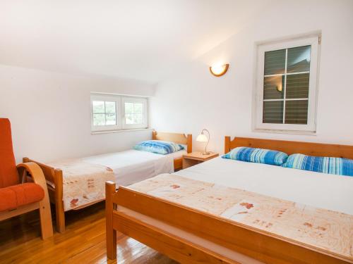 a bedroom with two beds and a chair and a window at Apartments Krš Medinski in Petrovac na Moru
