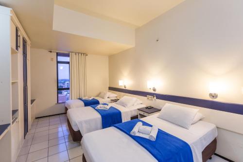 a hotel room with three beds and a window at Abbeville Hotel Torre I - Torre II in São Luís