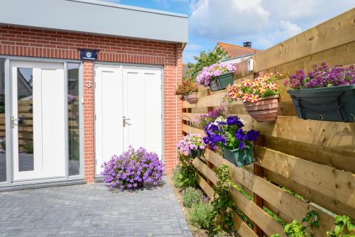 une clôture avec des fleurs en pot sur le côté d'une maison dans l'établissement BnB 't Kraaiennest, à De Cocksdorp