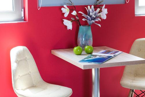 a table with a vase of flowers and two green apples at Menta City Boutique Hotel in Rethymno Town