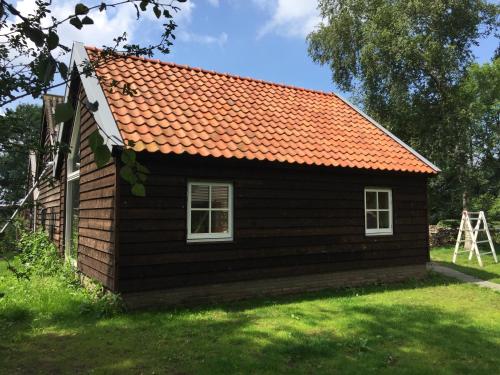 a small brown house with an orange roof at Huisje op Hamingen in Staphorst