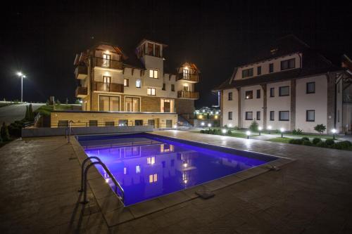 a swimming pool in front of a building at night at Zlatibor Hills in Zlatibor