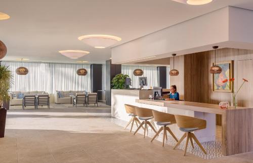 a lobby with a bar with a woman sitting at it at H10 Casa del Mar in Santa Ponsa