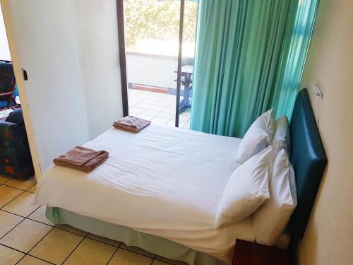 a bedroom with a bed with white sheets and pillows at Dumela Margate Flat No 3 in Margate