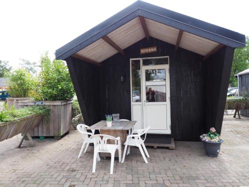 a table and chairs in front of a black shed at Chalet - Camping 't Dekske in Wintelre
