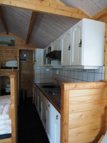 a kitchen with white cabinets and a bed in a room at Chalet - Camping 't Dekske in Wintelre