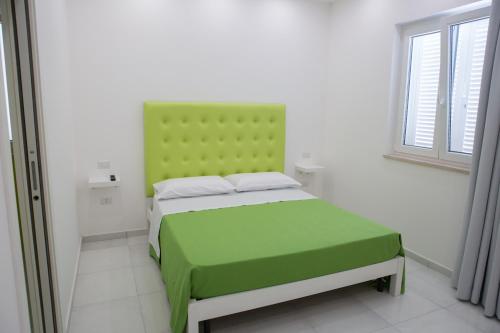 un letto con testiera verde in una stanza di Melissa B&B a Castellabate
