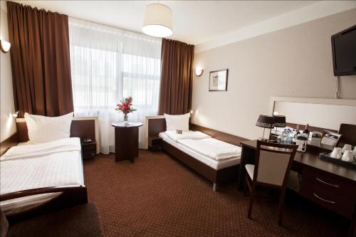 a hotel room with two beds and a desk at Hotel Diament Spodek in Katowice