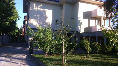 a white building with trees in front of it at Vila Ema Apartments and Rooms in Ljubljana