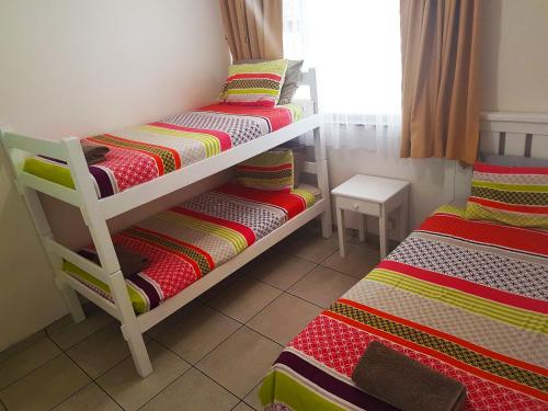 a bedroom with two bunk beds with colorful blankets at Dumela Margate Flat No 8 in Margate