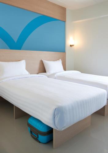 two beds in a hotel room with a suitcase under them at Hop Inn Hotel Makati Avenue Manila in Manila
