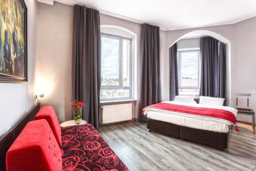 a hotel room with a bed and a red couch at Grand Boutique Hotel - dawny Hotel Kaliski Ratuszowy in Rzepin