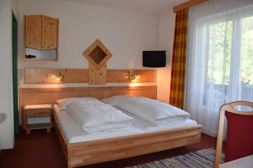 a bedroom with a bed and a window with a television at Pension Appartement Ambrosi in Heiligenblut