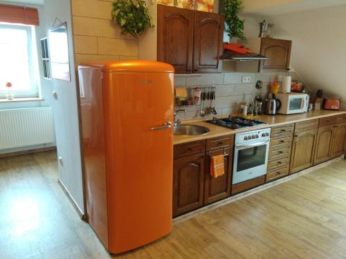 an orange refrigerator in a kitchen with wooden cabinets at Orange Loft Apartment in Kájov