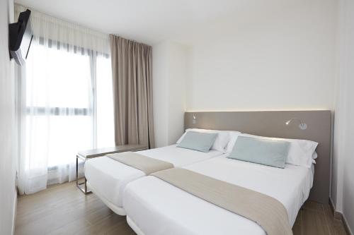 two beds in a hotel room with windows at Don Cesar Boutique Apartments in Benidorm