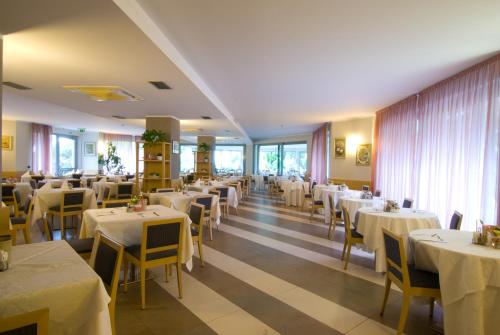 a dining room with white tables and yellow chairs at Hotel Oasi Wellness & Spa in Riva del Garda