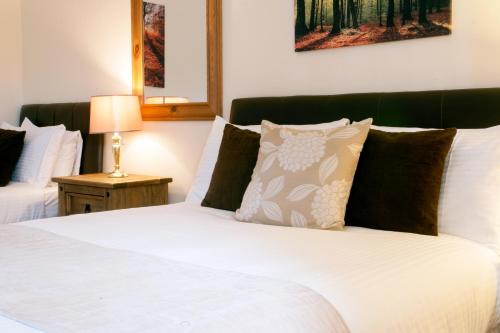 a bedroom with a bed with white sheets and pillows at Glenmoriston Arms Hotel in Invermoriston