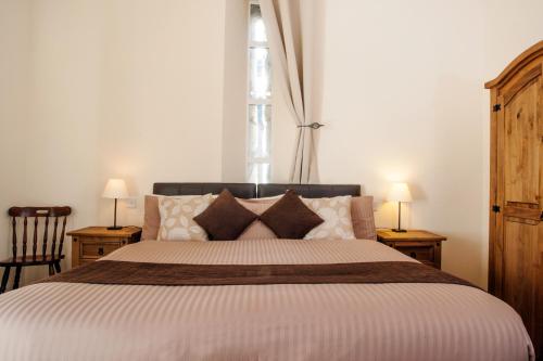 a bedroom with a large bed with two tables and two lamps at Glenmoriston Arms Hotel in Invermoriston