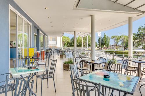 a patio with tables and chairs on a building at Hotel Ambassador in Caorle